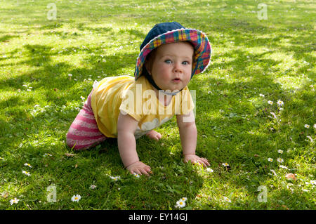 Portrait of a baby girl wearing a sunhat learning to crawl Stock Photo