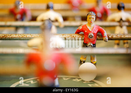 A old table top football player close up. Known as Foosball or babyfoot it's a much loved well worn player who's has the ball at his feet Stock Photo