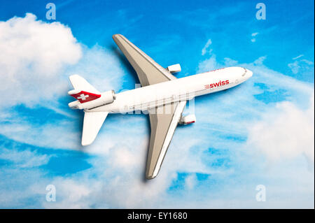 miniature toy airplane Swissair on a printed sky background Stock Photo