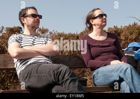 Couple sitting on a bench apart looking annoyed with each other Stock Photo