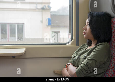 A young woman looks out the window at railway station Stock Photo