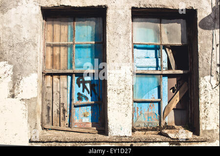 A broken, boarded up window in an old house Stock Photo