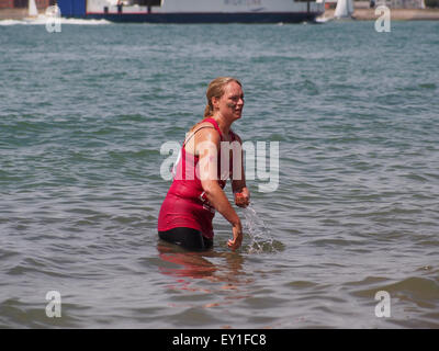 A lady cools down and washes mud from her skin in the sea after the Pretty Muddy Race For Life in Southsea Stock Photo
