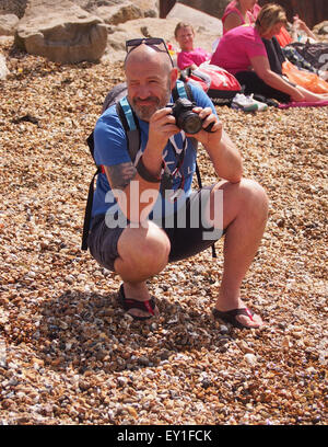 Middle aged man undertaking his hobby of photography on a beach Stock Photo