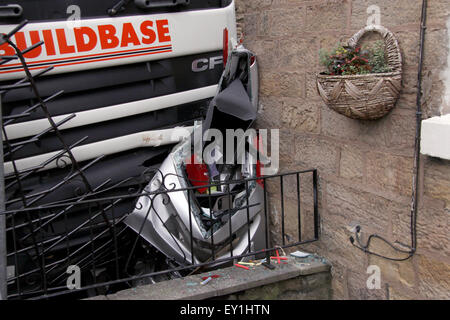 Truck loaded with heavy building materials mounts the pavement crashing into a public house and crushing a parked car in the UK Stock Photo