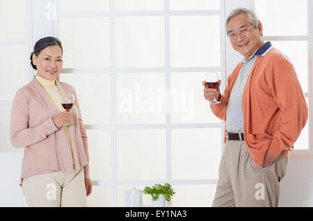 Senior couple holding a glass of red wine and smiling at the camera, Stock Photo
