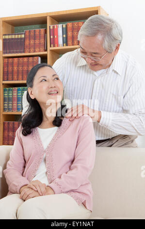 Senior man smiling at senior woman with hands on shoulder, Stock Photo