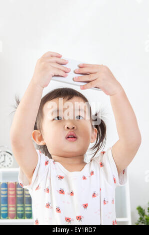 Little girl holding mobile phone and looking up, Stock Photo