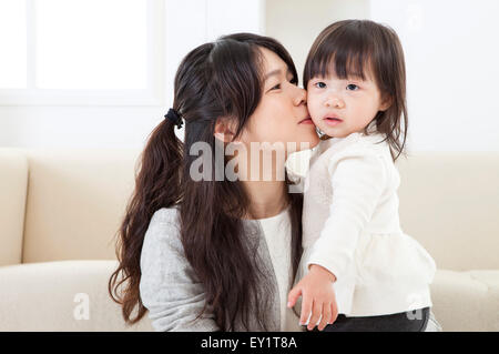 Mother kissing baby girl and looking away, Stock Photo
