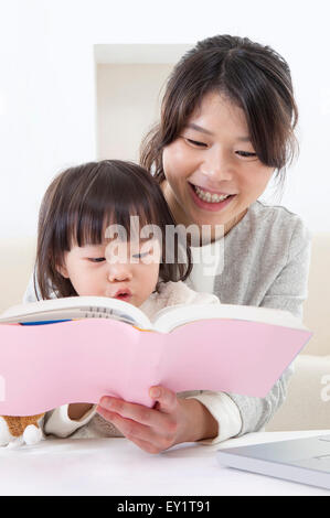 Mother and baby girl reading book together, Stock Photo