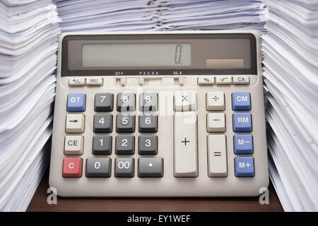 Pile of documents on desk stack up high with calculator on office desk Stock Photo