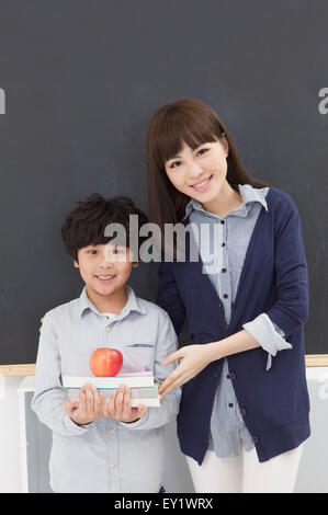 Young teacher and schoolboy standing in the classroom and smiling, Stock Photo