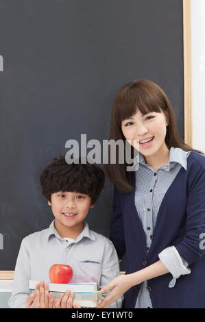 Young teacher and schoolboy standing in the classroom and smiling, Stock Photo