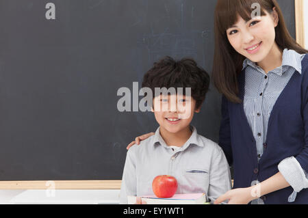 Young teacher and schoolboy standing in the classroom and smiling, Stock Photo