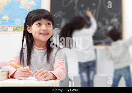 Children studying in the classroom and looking away with smile, Stock Photo