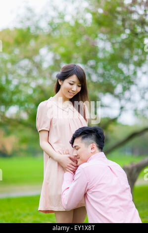 Young man listening with pregnant woman's abdomen, Stock Photo