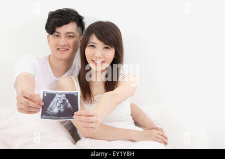 Young couple holding a pic and smiling at the camera, Stock Photo