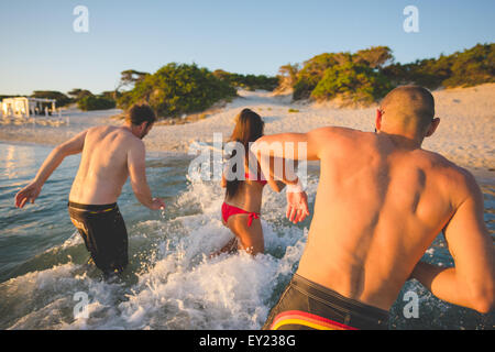 group of young multiethnic friends women and men at the beach in summertime having fun splashing around Stock Photo