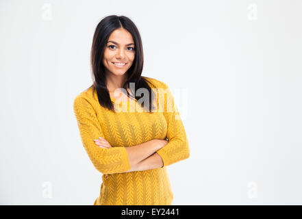 Happy young woman standing with arms folded isolated on a white background and looking at camera Stock Photo
