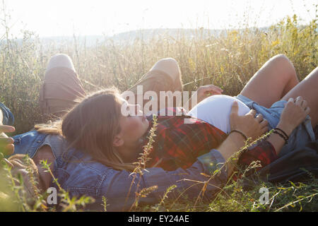 Young pregnant couple lying in field Stock Photo