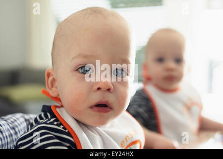 Portrait of staring baby twin brothers in high chairs Stock Photo