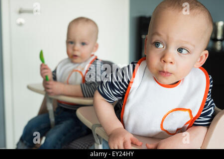 Baby twin brothers playing in high chairs Stock Photo
