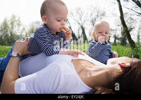 Baby twin brothers and mother having picnic in field Stock Photo