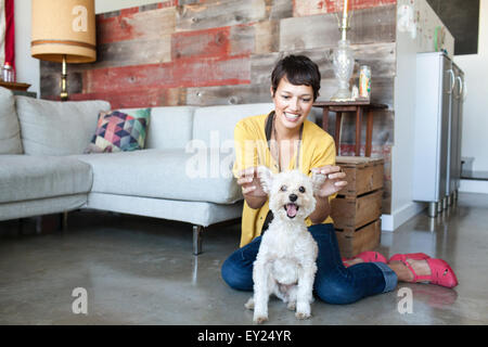 Young woman holding up dogs ears in living room