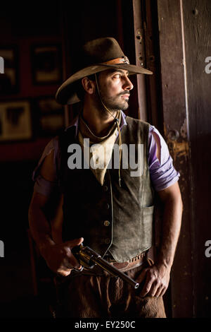Portrait of cowboy holding handgun in doorway on wild west film set, Fort Bravo, Tabernas, Almeria, Spain Stock Photo