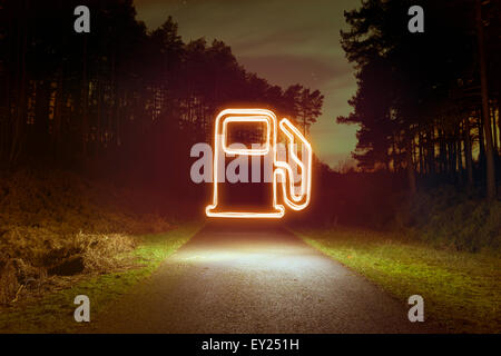 Glowing gas pump symbol above forest road at night Stock Photo