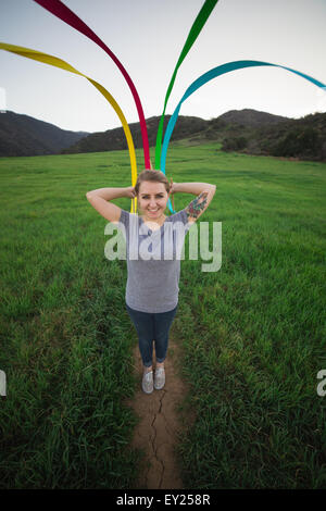 Portrait of young woman standing in field forming pattern with dance ribbons Stock Photo