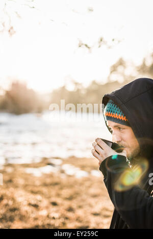 Portrait of young man drinking coffee at lakeside Stock Photo