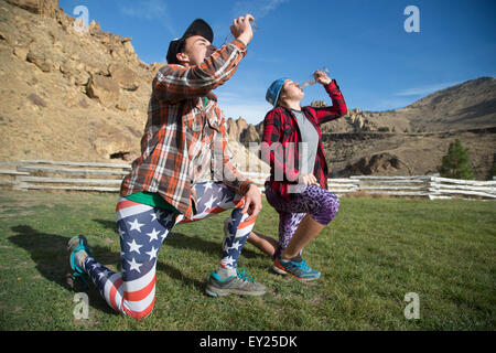 Friends kneeling and drinking, Smith Rock State Park, Oregon, US Stock Photo