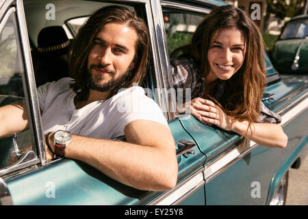 Young couple leaning out of vintage car windows Stock Photo