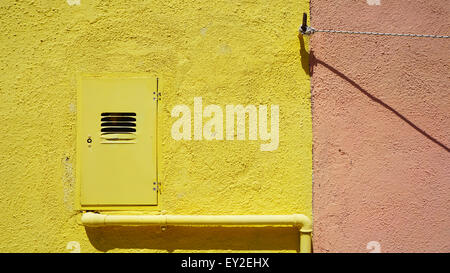 metal pipe and electric box on yellow color wall in Burano, Venice, Italy Stock Photo