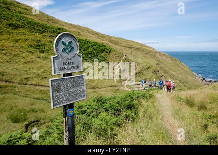 Sign on Wales Coast Path with hikers hiking at Porth Llanllawen Lleyn Peninsula / Pen Llyn Gwynedd North Wales UK Stock Photo