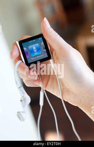 Close up of an Apple iPod nano, with headphones, held in a womans hand showing the voice memos screen. Stock Photo