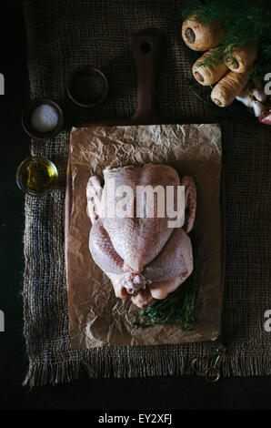 A seasoned chicken is displayed on a cutting board lined with butchers paper. Stock Photo