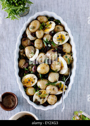 Baby Potatoes with Sun-Dried Tomatoes and Caper Dressing displayed in a large oval bowl. Stock Photo