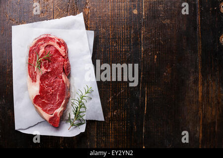 Raw fresh marbled meat Black Angus Steak and rosemary on dark wooden background Stock Photo