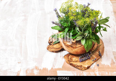 Bouquet of fresh herbs dill, thyme, sage, lavender, mint, basil. Olive wood kithchen tools. Stock Photo