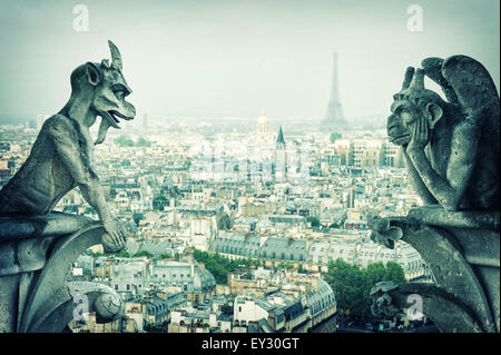 Stone demons gargoyle und chimera with Paris city on background. View from Notre Dame de Paris. Vintage style toned picture Stock Photo
