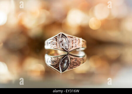 A diamond ring with a reflection, against a golden yellow light blurred background Stock Photo