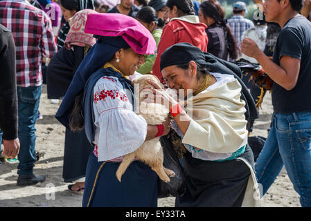 A native woman pets a puppy held by another old lady at local market. Otavalo, Ecuador. Stock Photo