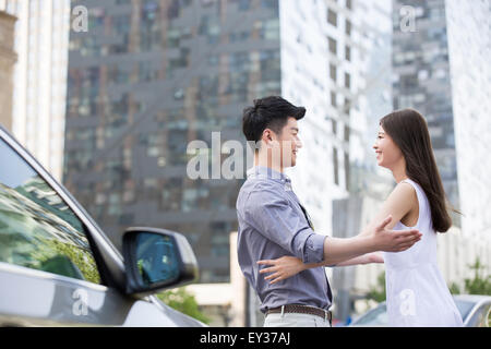Young couple embracing next to their car Stock Photo