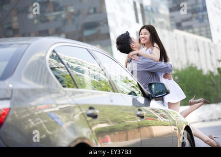Young couple embracing next to their car Stock Photo