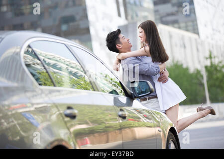 Young couple embracing next to their car Stock Photo