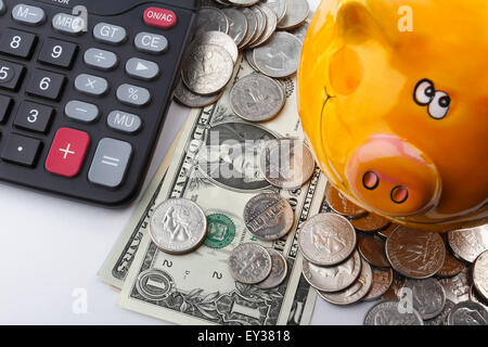 US Dollar coins and notes, together with a piggy bank and a calculator. Stock Photo