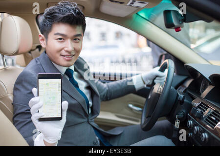 Chauffeur showing smart phone in a car Stock Photo