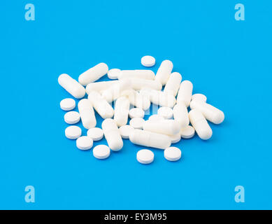 the small group of white tablets and pills is scattered on a surface Stock Photo